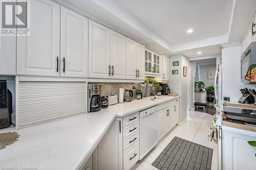 Kitchen featuring backsplash, white cabinets, sink, light tile patterned floors, and dishwasher - 3100 Kirwin Avenue Unit# 2102, Mississauga, ON - Indoor Photo Showing Kitchen