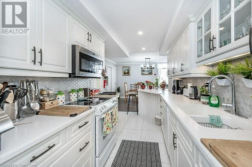 Kitchen featuring sink, light tile patterned floors, pendant lighting, white electric range, and white cabinetry - 3100 Kirwin Avenue Unit# 2102, Mississauga, ON - Indoor Photo Showing Kitchen