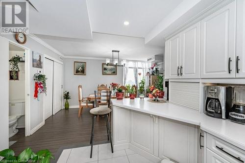 Kitchen featuring crown molding, decorative light fixtures, an inviting chandelier, light hardwood / wood-style flooring, and white cabinetry - 3100 Kirwin Avenue Unit# 2102, Mississauga, ON - Indoor Photo Showing Kitchen