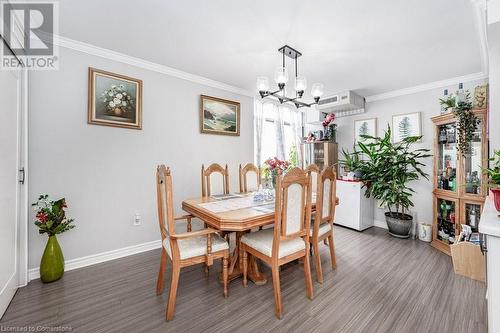 Dining room with dark hardwood / wood-style floors, an inviting chandelier, and crown molding - 3100 Kirwin Avenue Unit# 2102, Mississauga, ON - Indoor Photo Showing Dining Room