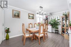 Dining room with dark hardwood / wood-style floors, an inviting chandelier, and crown molding - 