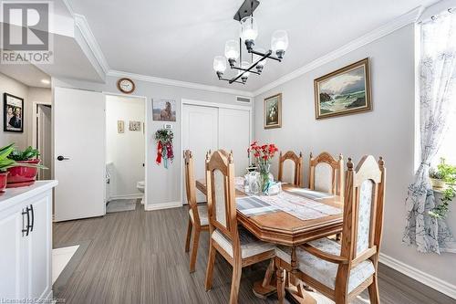 Dining space with a chandelier, wood-type flooring, and crown molding - 3100 Kirwin Avenue Unit# 2102, Mississauga, ON - Indoor Photo Showing Dining Room