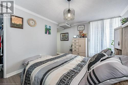 Bedroom with a wall mounted AC, wood-type flooring, a textured ceiling, and ornamental molding - 3100 Kirwin Avenue Unit# 2102, Mississauga, ON - Indoor Photo Showing Bedroom