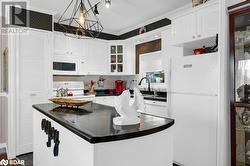 Kitchen with pendant lighting, white cabinetry, white appliances, and ornamental molding - 