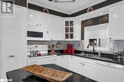 Kitchen with crown molding, sink, white cabinets, and white appliances - 