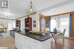 Kitchen with ornamental molding, dark wood-type flooring, wooden walls, decorative light fixtures, and white cabinets - 