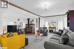 Carpeted living room featuring a wood stove, ornamental molding, and a chandelier - 