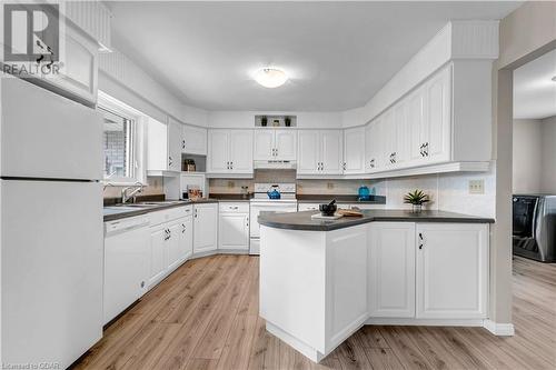 Kitchen with white appliances, white cabinets, light hardwood / wood-style flooring, decorative backsplash, and washer / dryer - 5819 Wellington Cty Rd 7, Guelph, ON 