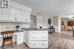 Kitchen with white cabinets, light hardwood / wood-style floors, kitchen peninsula, and backsplash - 