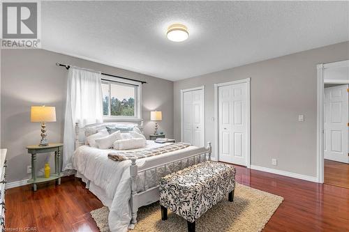 Bedroom with two closets, a textured ceiling, and dark hardwood / wood-style floors - 5819 Wellington Cty Rd 7, Guelph, ON 