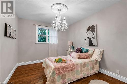 Bedroom featuring a textured ceiling, dark hardwood / wood-style flooring, and an inviting chandelier - 5819 Wellington Cty Rd 7, Guelph, ON 