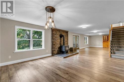 Unfurnished living room featuring a wood stove and wood-type flooring - 5819 Wellington Cty Rd 7, Guelph, ON 