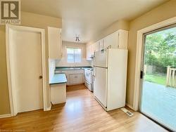 Kitchen with white appliances, backsplash, white cabinets, sink, and light wood-type flooring - 