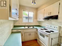 Kitchen with white electric range, light hardwood / wood-style flooring, white cabinetry, and sink - 