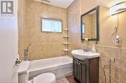 Full bathroom featuring vanity, tile patterned floors, tiled shower / bath combo, toilet, and tile walls - 