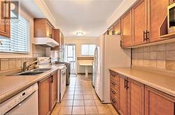 Kitchen featuring decorative backsplash, sink, light tile patterned flooring, and white appliances - 