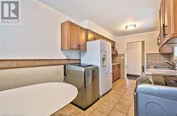 Kitchen featuring washer and clothes dryer, white fridge with ice dispenser, sink, and light tile patterned floors - 