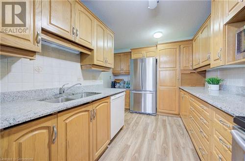 Kitchen featuring light stone counters, sink, stainless steel appliances, and light hardwood / wood-style floors - 375 King Street N Unit# 503, Waterloo, ON - Indoor Photo Showing Kitchen With Double Sink