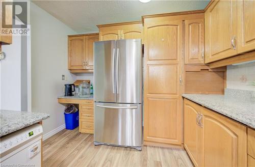 Kitchen with white dishwasher, decorative backsplash, stainless steel fridge, light wood-type flooring, and light stone countertops - 375 King Street N Unit# 503, Waterloo, ON - Indoor Photo Showing Kitchen