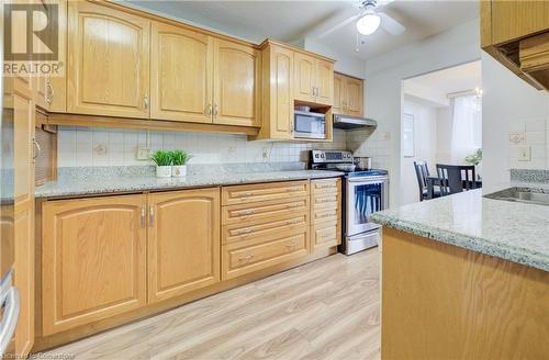 Kitchen featuring decorative backsplash, light stone countertops, and stainless steel appliances - 375 King Street N Unit# 503, Waterloo, ON - Indoor Photo Showing Kitchen