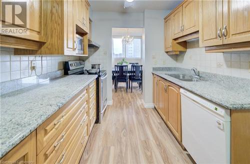 Kitchen featuring stainless steel range with electric stovetop, white dishwasher, sink, light hardwood / wood-style flooring, and light stone countertops - 375 King Street N Unit# 503, Waterloo, ON - Indoor Photo Showing Kitchen With Double Sink