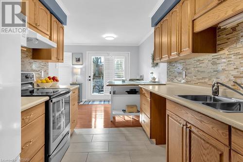 Kitchen featuring tasteful backsplash, stainless steel range with electric stovetop, crown molding, sink, and light hardwood / wood-style flooring - 529 Nova Scotia Court Unit# 18, Woodstock, ON - Indoor Photo Showing Kitchen With Double Sink