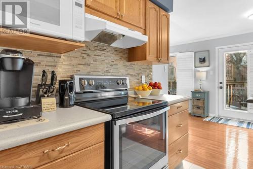 Kitchen featuring backsplash, stainless steel electric range oven, light hardwood / wood-style floors, and ornamental molding - 529 Nova Scotia Court Unit# 18, Woodstock, ON - Indoor Photo Showing Kitchen