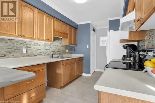 Kitchen with decorative backsplash, crown molding, stove, and sink - 529 Nova Scotia Court Unit# 18, Woodstock, ON - Indoor Photo Showing Kitchen With Double Sink