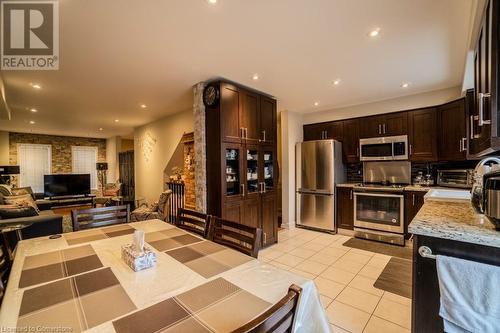 Kitchen with backsplash, appliances with stainless steel finishes, light tile patterned flooring, light stone counters, and dark brown cabinetry - 1480 Britannia Road W Unit# 143, Mississauga, ON - Indoor Photo Showing Kitchen