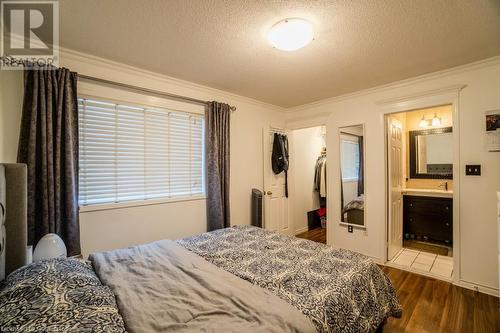 Bedroom with ensuite bath, dark hardwood / wood-style flooring, a textured ceiling, a closet, and ornamental molding - 1480 Britannia Road W Unit# 143, Mississauga, ON - Indoor Photo Showing Bedroom