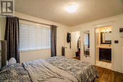 Bedroom with ensuite bath, dark hardwood / wood-style flooring, a textured ceiling, a closet, and ornamental molding - 