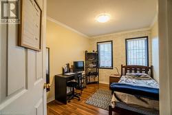 Bedroom featuring a textured ceiling, dark hardwood / wood-style floors, ornamental molding, and brick wall - 