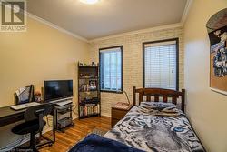 Bedroom featuring hardwood / wood-style floors, a textured ceiling, crown molding, and brick wall - 