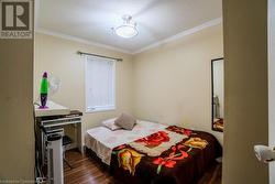 Bedroom with a textured ceiling, ornamental molding, and dark wood-type flooring - 