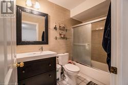 Full bathroom with vanity, combined bath / shower with glass door, tile patterned flooring, toilet, and tile walls - 