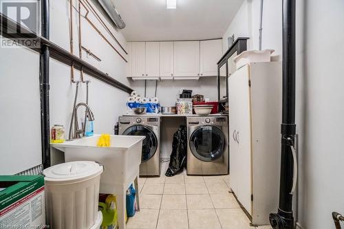 Laundry area featuring washer and clothes dryer, cabinets, light tile patterned floors, and sink - 1480 Britannia Road W Unit# 143, Mississauga, ON - Indoor Photo Showing Laundry Room