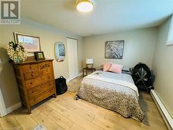 Bedroom with light wood-type flooring, a baseboard radiator, and a closet - 