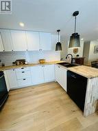 Kitchen featuring black appliances, white cabinetry, and pendant lighting - 