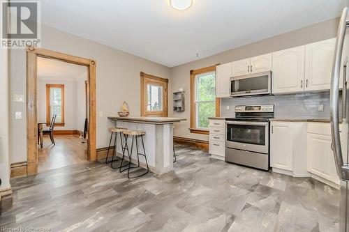 Kitchen featuring backsplash, white cabinets, a kitchen breakfast bar, ornamental molding, and appliances with stainless steel finishes - 3212 Roseville Road, Roseville, ON - Indoor Photo Showing Kitchen