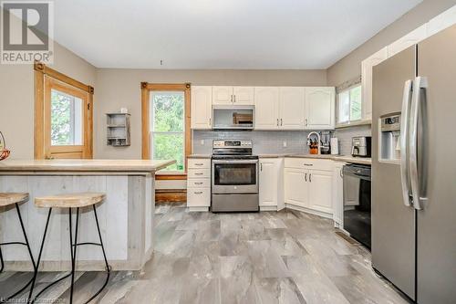 Kitchen with white cabinets, decorative backsplash, stainless steel appliances, and a breakfast bar area - 3212 Roseville Road, Roseville, ON - Indoor Photo Showing Kitchen