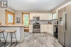 Kitchen with white cabinets, decorative backsplash, stainless steel appliances, and a breakfast bar area - 