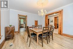 Dining area with crown molding, light hardwood / wood-style floors, and a notable chandelier - 