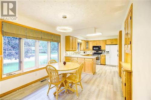 Kitchen with kitchen peninsula, tasteful backsplash, white refrigerator with ice dispenser, stainless steel gas stove, and light hardwood / wood-style floors - 3 Maitland Street, Blandford, ON - Indoor