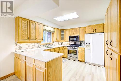 Kitchen featuring stainless steel gas stove, light hardwood / wood-style flooring, white refrigerator with ice dispenser, kitchen peninsula, and decorative backsplash - 3 Maitland Street, Blandford, ON - Indoor Photo Showing Kitchen