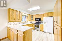 Kitchen featuring stainless steel gas stove, light hardwood / wood-style flooring, white refrigerator with ice dispenser, kitchen peninsula, and decorative backsplash - 