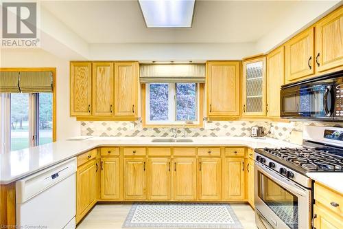 Kitchen with kitchen peninsula, decorative backsplash, stainless steel gas range oven, white dishwasher, and sink - 3 Maitland Street, Blandford, ON - Indoor Photo Showing Kitchen