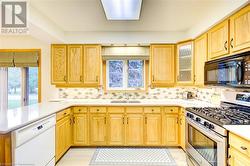 Kitchen with kitchen peninsula, decorative backsplash, stainless steel gas range oven, white dishwasher, and sink - 