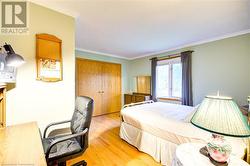 Bedroom featuring light wood-type flooring, ornamental molding, and a closet - 