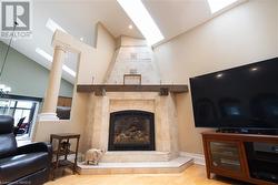 Living room with light wood-type flooring, a fireplace, and high vaulted ceiling - 