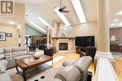 Living room with a fireplace, light hardwood / wood-style floors, high vaulted ceiling, and ceiling fan - 